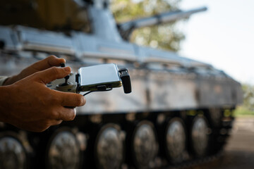 man with a UAV control panel in his hands, a drone flying above the tank in the background in...