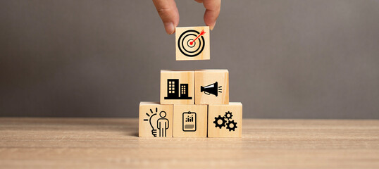 concepts related to marketing. Product production planning. A man places a wooden block with a target and an arrow on a wooden block with a manufacturing process icon. 