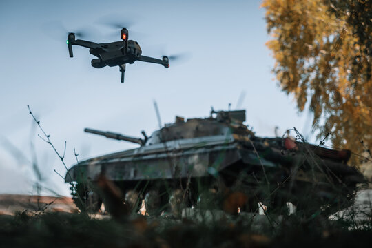 drone flying above the tank in the background in nature. help of reconnaissance drones in modern warfare.