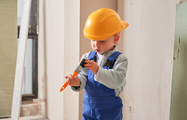 Little boy construction worker painting wall with brush in apartment under renovation. Child...