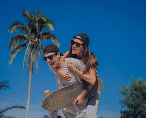 Young happy couple with skateboards enjoy longboarding at the skatepark