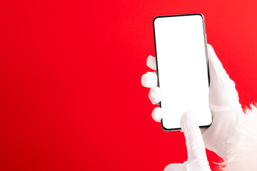 Santa claus hands holding smartphone with copy space on red background