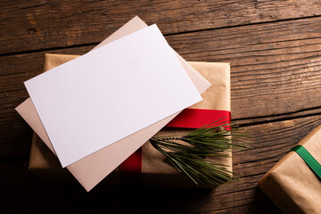 Christmas gifts with decorations and white card and copy space on wooden background