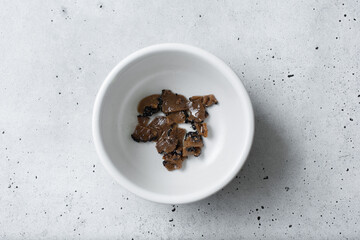 A top down view of a condiment cup of canned black truffle.