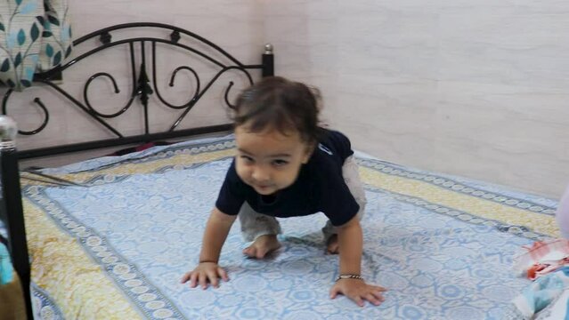 cute toddler baby boy trying to stand for the first time at bed at home