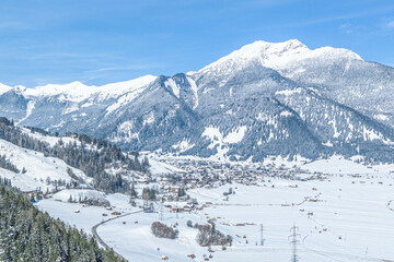 Fototapeta na wymiar Die winterliche Tiroler Zugspitz Arena - Blick auf den Wintersportort Lermoos vor der Silhouette des Daniel-Massivs