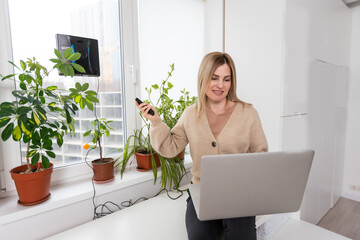 Woman cleaning windows at home with robotic cleaner.