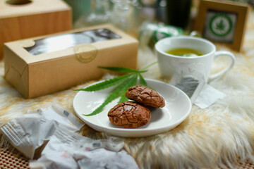 Cannabis cookies, medicine in food, THC and CBD brownies, medicine and cannabis sprouts on a board against the background of growth. Recreational and medical cannabis concepts.