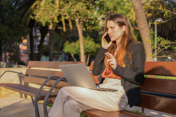 Casual businesswoman talking to the mobile while working sitting outdoors