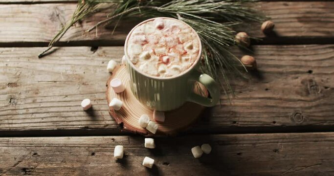Video of mug of chocolate, marshmallows, christmas decorations and copy space on wooden background