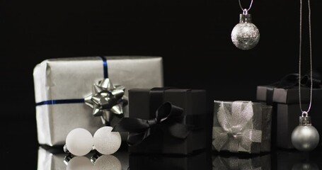 Video of silver baubles christmas decorations and gifts with copy space on black background