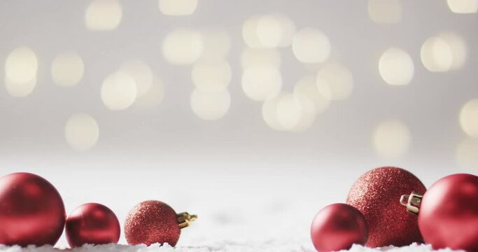 Video of red baubles christmas decorations with copy space on snow background