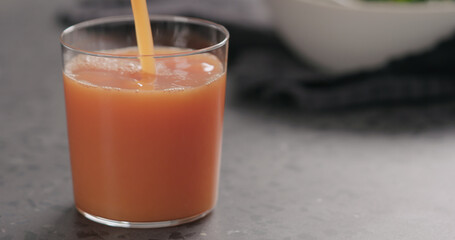 pour grapefruit juice into glass on concrete surface with copy space