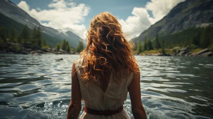 Foto op Aluminium A woman in a summer dress and open long hair half in a mountain lake taken from behind © Hannes