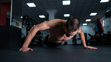 Fototapeta na wymiar Muscular shirtless man doing push ups in the gym. 