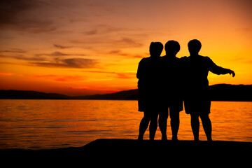trzy starsze Panie, przyjaciółki podziwiają zachód słońca na plaży nad morzem