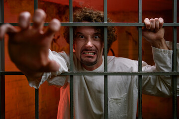 Angry crazy man prisoner and psychiatric hospital patient in cage