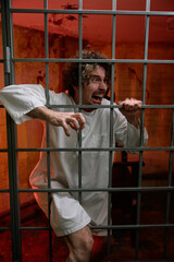 Angry crazy man prisoner and psychiatric hospital patient in cage