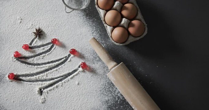Video of christmas tree drawn in flour, eggs, roler and copy space on black background