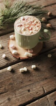 Vertical video of mug of chocolate, marshmallows, decorations and copy space on wooden background