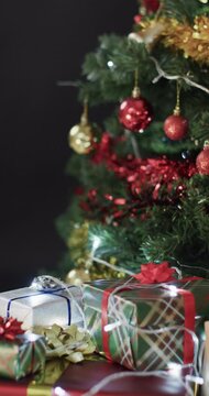 Vertical video of christmas tree with presents and decorations and copy space on black background