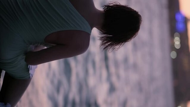 Silhouette of a young woman against the background of the sea, squeaking a letter and throwing sheets of paper into the wind