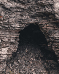 Rocky cave entrance with detailed stone wall. Vertical photo.