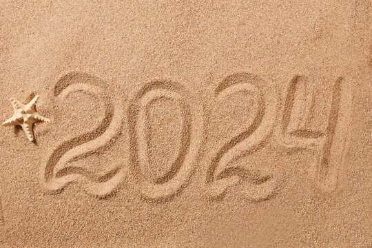 Happy New Year 2024 greeting card. The numbers 2024 on the sand on the beach, a starfish. Natural background.