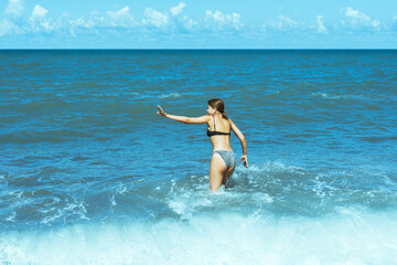 Teenage girl running towards sea splashing waves