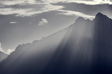 Monochrome shot of voluminous streaks of the evening sun over the ridge of the Hahnenkamm mountains...