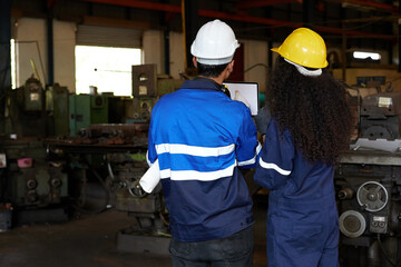 back view workers or engineers looking and pointing to machine in the factory