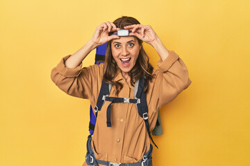 Middle aged woman mountaineer gear ready on yellow background