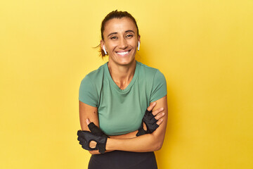 Athletic middle-aged woman on yellow backdrop laughing and having fun.
