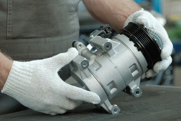 Auto parts. The new compressor for the air conditioner is in the hands of an auto mechanic....