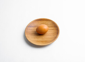 Wooden eco-friendly tableware for healthy lifestyle design. A chicken egg lies on a wooden plate.