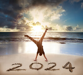 Excited Young man handstand on the beach.happy new year 2024 concept.