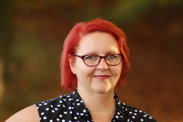 A happy, red-haired girl stands in the autumn forest