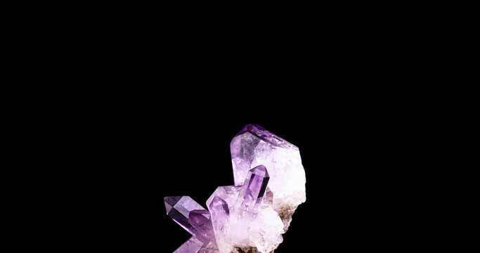 clear amethyt crystal rotating 360&deg; loop isolated on black background. macro detail close-up rough raw unpolished semi-precious gemstone.

