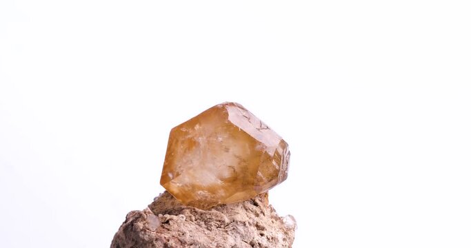 orange rhombohedral calcite on matrix rotating 360&deg; loop isolated on white background. macro detail  background. close-up Rough raw unpolished semi-precious gemstone.
