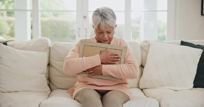 Sad, senior and a woman with a photo for a memory, grief and depression frfom loss in a home. Idea, anxiety and an elderly person hugging a picture frame to remember with emotion, lonely or missing
