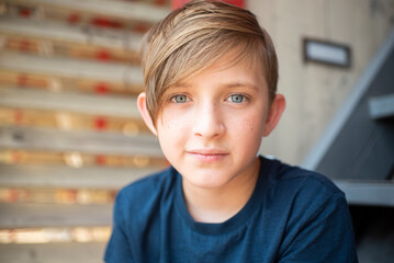 portrait of a serious 11 year old boy with blue eyes and light brown hair, looking at the camera.