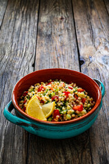 Tabbouleh salad - bulgur groats, tomatoes, cucumber, parsley, lemon, onion and fresh mint leaves on wooden background
