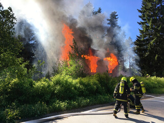 Fototapeta premium Firefighters put out burning house