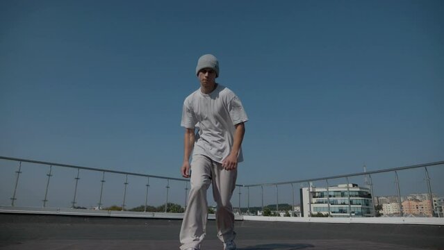 The guy coolly dances breakdance on the roof of the house. A man dances an energetic athletic dance.	
