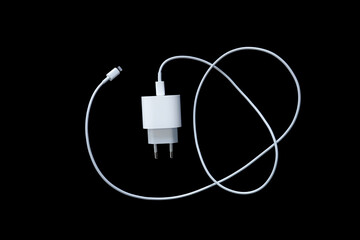 Top view of phone charger and USB cable on black background