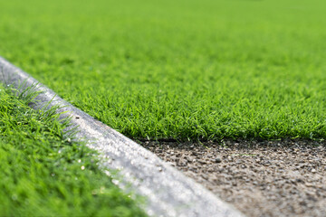 Evergreen artificial grass close-up. Short cut real grass on the edge of the pitch in the stadium. Artificial grass close-up. Artificial turf background.  - obrazy, fototapety, plakaty