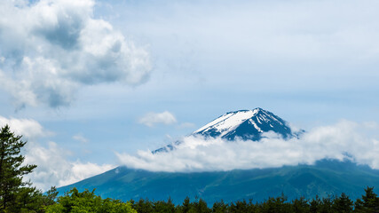 The snowy and cloudy peak of Mount Fuji is a symbol of Japan and a popular tourist destination. Copy space background