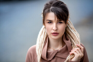 Close portrait of a beautiful slim sexy caucasian brunette girl with dreadlocks in rose pink hoodie...