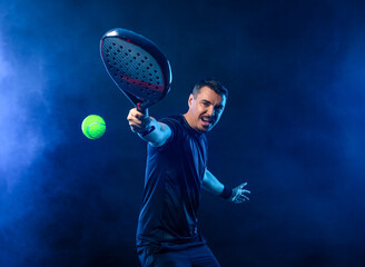 Padel tennis open tour player. Man athlete with paddle tenis racket on black background. Sport concept. Download a high quality photo for sports website.
