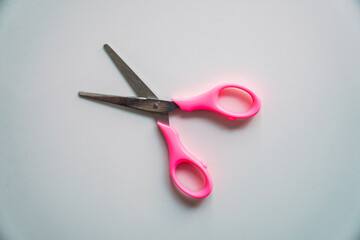 Scissors with pink handle on white background, top view